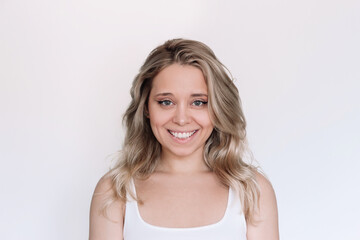 Fototapeta premium Portrait of a young attractive cheerful caucasian smiling blonde woman with wavy hair isolated on a white background. Charming girl with green eyes