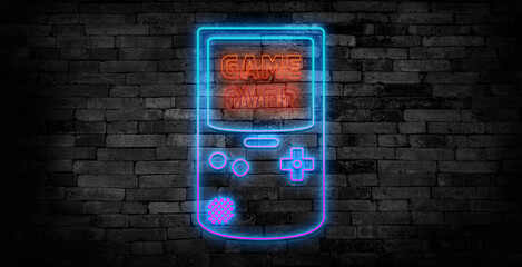 Game over text on gaming console neon sign on a drak brick wall background.