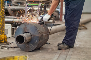 Worker using an angle grinder, making a screw conveyor