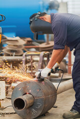 Worker using an angle grinder, making a screw conveyor