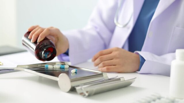 Female pharmacist counting medicine on tray.