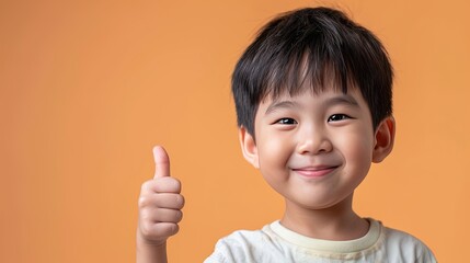 Asian boy happily smiles and shows thumbs up on deep yellow background. Everything is ok, happy time
