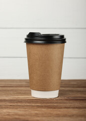 Brown paper coffee cup over white wall