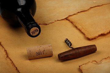 Bottle of wine with cork and opener on brown paper