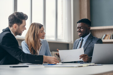 Concentrated young couple listening to financial advisor while sitting at the office desk together