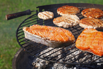 Chicken or turkey burger and salmon steak on grill