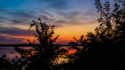 Obraz premium Beautiful scenic view of a vibrant sunrise over the ottawa river with the silhouette of trees on a cold morning in october.