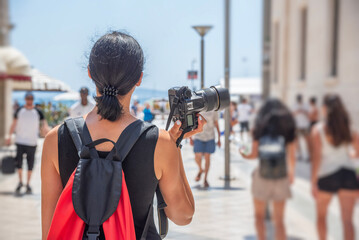 Tourist with a camera photographing the streets and points of interest on a sunny day.