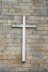 A large symbol of Christianity on a stone wall. This is a traditional cross.