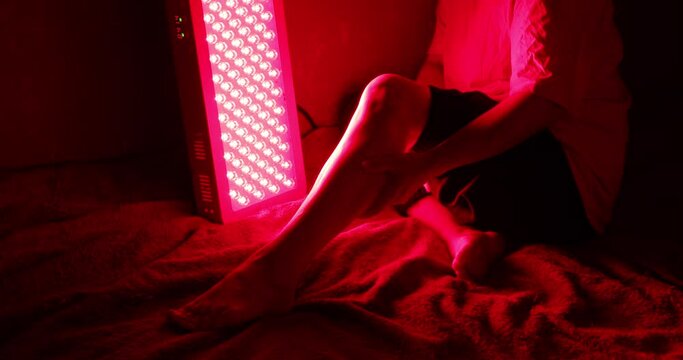 Closeup of sore leg of a person treating with the red light therapy panel