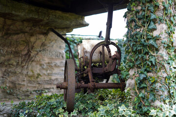 An old bell by the house, which is decorated with a metal cat and is attached to a wooden beam.