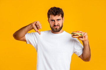Man Holding Burger Gesturing Thumb Down Disapproving Unhealthy Nutrition, Studio