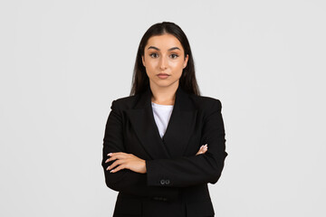 Entrepreneurship. Portrait of businesswoman in black jacket, posing looking at camera over gray studio background