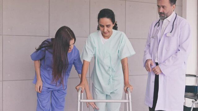 Physical therapy after surgery, doctor and nurse help woman patient walk using walker