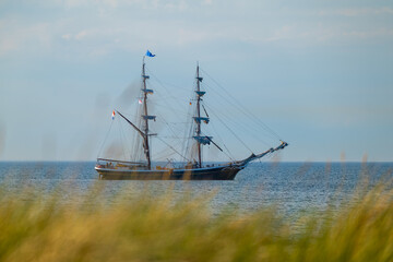 Seegelboot auf dem Meer hinter Dünen