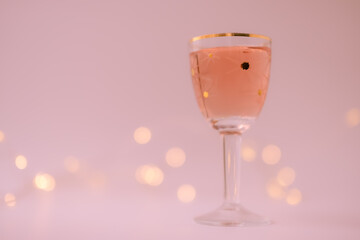 Rose wine in a vintage star glass. Bokeh. Pale violet red color background. Copy space. Shallow depth of field.