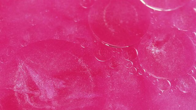 Abstract background. Sparkling fluid. Colorful oil circles. Fat round spots floating motion on vibrant pink glitter particles water surface in shiny ink art.