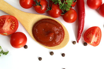 A wooden spoon with tomato sauce and vegetables lies on a white background.