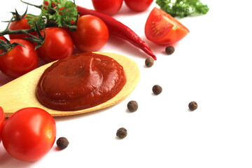 A wooden spoon with tomato sauce and vegetables lies on a white background.