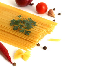Vegetables and long dry spaghetti lie on a white background.	