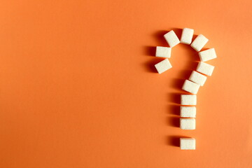 On an orange background lies a square sugar lined with a question mark.