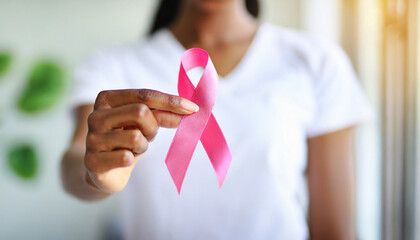 Woman's hand holds pink ribbon, symbolizing breast cancer awareness and medical care
