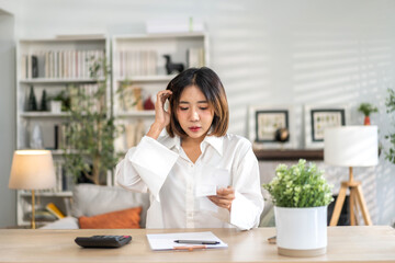 Smiling asian woman using calculator and calculate bills on laptop, paying bill, credit card, finance, tax, vat, credit card,  payment, tax refund, budget, debt, money.financial and accounting concept