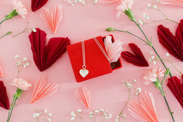 Valentines day flat lay. Stylish pink and red hearts, flowers and heart necklace on pink...