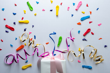 Creative composition made with gift box and party streamers on white background. Minimal celebration party concept.