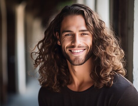 a smiling man with long curly hair