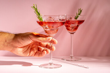 Refreshing cocktail with rosemary in a glass on a bright background. Summer party concept.