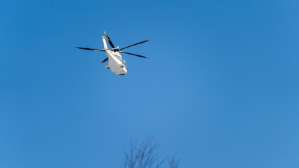 White helicopter on blue sky background, Close-up, selective focus, tinted image. Helicopter flight, delivery of passengers by air