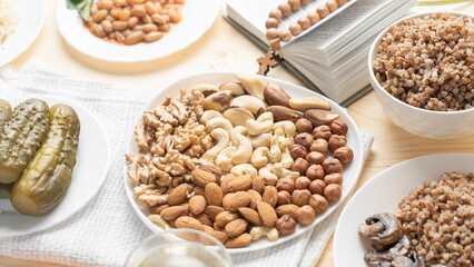 Lenten food in Lent on wooden background, nuts on plate, cashews, hazelnuts, almonds, walnuts