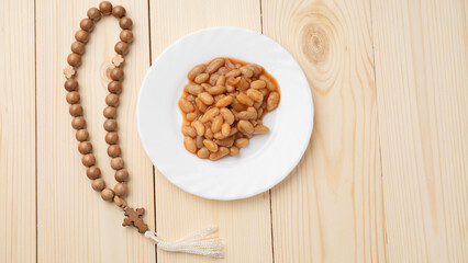 Beans canning in tomato sauce and orthodox prayer beads, Lenten food in Lent on wooden background