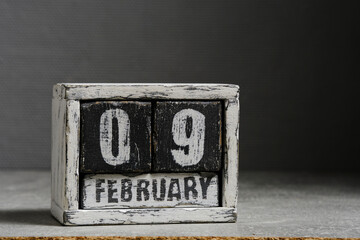 February 09 on wooden calendar, on dark gray background.