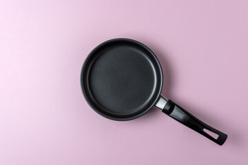 Small frying pan on pastel pink background. Minimal food concept.