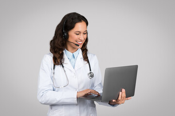 Telemedicine concept. Female doctor with laptop and headset making online consultation talking to patient via video call