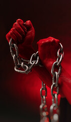 bloodied hands clenched into fists in the shackles of a metal chain symbolize slavery, protest and...