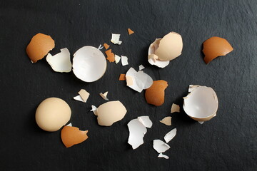 A lot of eggshells lie on a black background.	