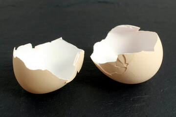 Two parts of the shell of one egg lie on a black background.	