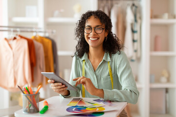 Joyful designer with tablet and color wheel in bright studio