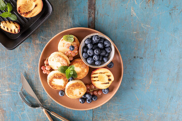 Cottage cheese pancakes with fresh blueberries, currants and peaches on a plate. Healthy and delicious breakfast for the holiday.