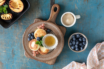 Cottage cheese pancakes, fritters with fresh blueberries, currants and peaches on a plate.