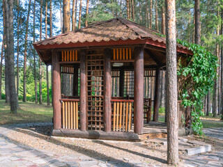 A gazebo made of wooden logs for relaxing in the forest and protection from sunlight and rain. A...