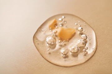 A drop of transparent cosmetic gel on a beige background.