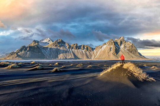 Hiker enjoying sunset at Vestrahorn and its black sand beach in Iceland