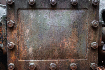 boiler plate on an abandoned boiler outside in the elements, background has a heavy texture of rust and old nuts and bolts are prominent - obrazy, fototapety, plakaty