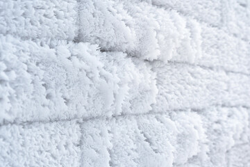 A perspective view of a brick wall. The surface of the bricks is covered with a thick coat of frost flakes. Background.