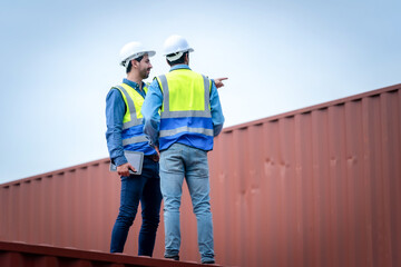 Engineer team wears PPE checking container storage with cargo container background at sunset. Logistics global import or export shipping industrial concept.