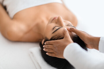 Serene eastern woman receiving head massage at spa